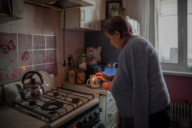 Valentyna Kucherenko, 75, lights a gas stove to keep warm in her flat during a heating outage following Russian strikes in Kharkiv on February 4, 2026, amid the Russian invasion of Ukraine. (Photo by Ivan SAMOILOV / AFP)