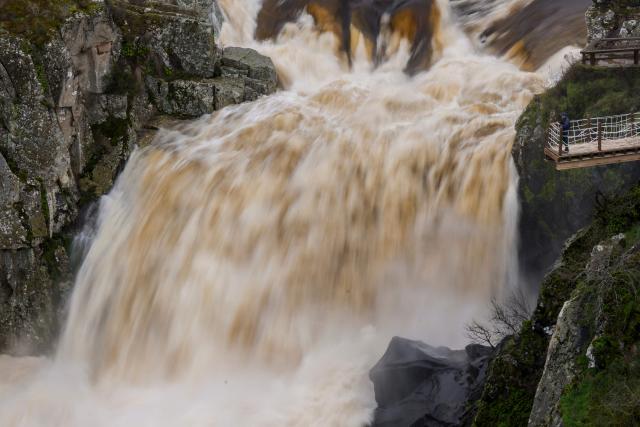 A person watches the 'Pozo de los Humos' waterfall (Well of Smoke) from a scenic viewpoint on the Uces River which is seeing an extraordinarily high flow due to snowmelt and heavy rains affecting the country, on February 4, 2026 near Masueco in the province of Salamanca. A storm bringing what weather forecasters called "extraordinary" rain battered the Iberian peninsula today, forcing thousands of people in southern Spain from their homes, shutting schools and cancelling trains. Spanish weather agency AEMET placed parts of the southern region of Andalusia under the highest red alert for torrential rain, warning that Storm Leonardo risked triggering floods and landslides. (Photo by CESAR MANSO / AFP)