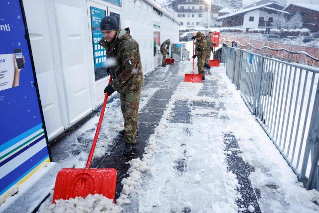 Italian military personnel shovel snow to clear the entrance outside the Olympic Stadium on the way to the media centre during the Milano Cortina 2026 Winter Olympic Games in Cortina d'Ampezzo on February 4, 2026. (Photo by Odd ANDERSEN / AFP)
