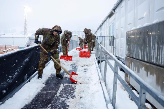 Italian military personnel shovel snow to clear the entrance outside the Olympic Stadium on the way to the media centre during the Milano Cortina 2026 Winter Olympic Games in Cortina d'Ampezzo on February 4, 2026. (Photo by Odd ANDERSEN / AFP)