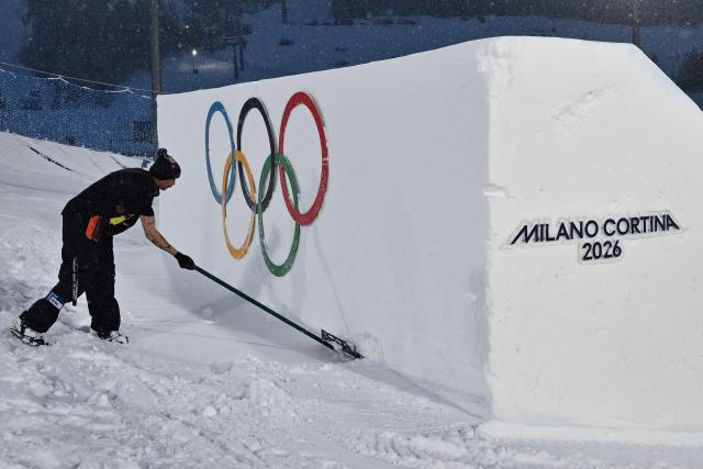 A worker shovels snow ahead of the snowboard men's big air qualifications during the Milano Cortina 2026 Winter Olympic Games at Livigno Snow Park, in Livigno (Valtellina), on February 4, 2026. (Photo by Jeff PACHOUD / AFP)