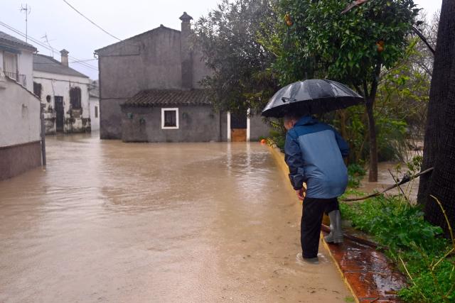 A man crosses a flooded street in Jimera de Libar, southern Spain, on February 4, 2026 amid Storm Leonardo. A storm unleashing up to 35 centimetres (14 inches) of rain in 24 hours battered the Iberian Peninsula today, forcing thousands of people in southern Spain from their homes, shutting schools and cancelling trains. Spanish weather agency AEMET placed parts of the southern region of Andalusia under the highest red alert for the torrential rain dumped by Storm Leonardo. (Photo by JORGE GUERRERO / AFP)