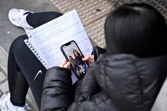 A teenager scrolls through social media on her phone in the Spanish Basque city of San Sebastian on February 4, 2026. Spain will seek to ban social media for under-16s to protect them from harmful content such as pornography and violence, Prime Minister Pedro Sánchez said yesterday, drawing a furious response from X owner Elon Musk. (Photo by ANDER GILLENEA / AFP)