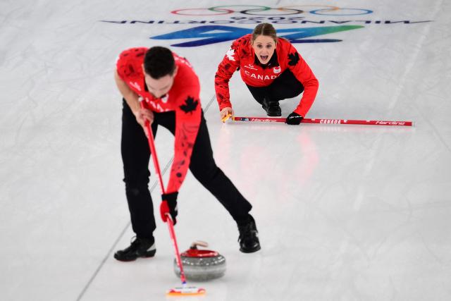 Canada's Jocelyn Peterman (Rear) guides Canada's Brett Gallant in the curling mixed doubles round robin between Canada and Czech Republic during the Milano Cortina 2026 Winter Olympic Games at the Cortina Curling Olympic Stadium in Cortina d’Ampezzo on February 4, 2026. (Photo by Marco BERTORELLO / AFP)