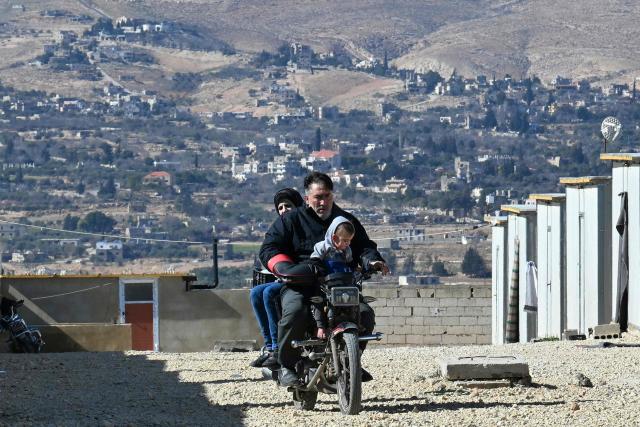 A man rides a motorcycle while carrying a toddler and a woman along at the Imam Ali Housing Compound, where displaced Lebanese and Syrian refugee Shiite Muslims take refuge by the city of Hermel in Lebanon's northeastern Bekaa valley on February 4, 2026. (Photo by Joseph EID / AFP)