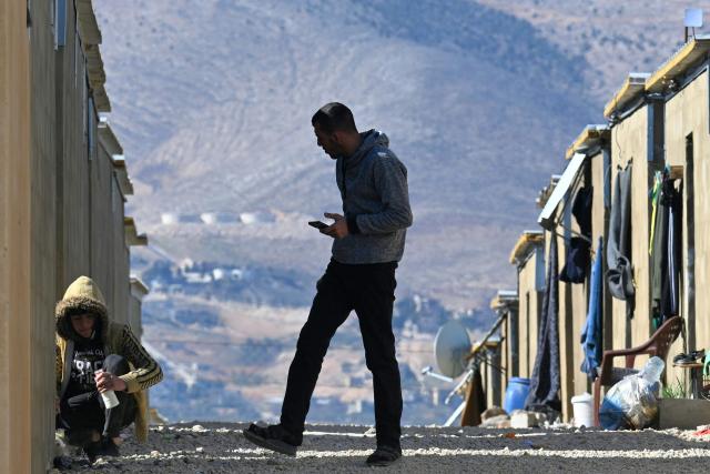 A man walks between shelters at the Imam Ali Housing Compound, where displaced Lebanese and Syrian refugee Shiite Muslims take refuge by the city of Hermel in Lebanon's northeastern Bekaa valley on February 4, 2026. (Photo by Joseph EID / AFP)