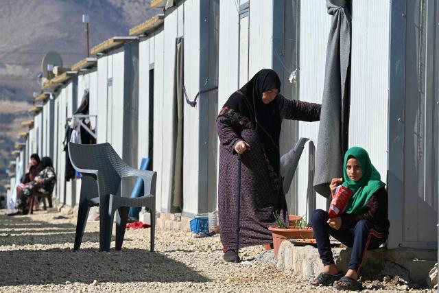 TOPSHOT - An elderly woman and a girl are pictured outside shelters at the Imam Ali Housing Compound, where displaced Lebanese and Syrian refugee Shiite Muslims take refuge by the city of Hermel in Lebanon's northeastern Bekaa valley on February 4, 2026. (Photo by Joseph EID / AFP)