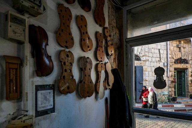 Women walk outside the workshop of Palestinian musical instrument maker Shehada Shalalda in Ramallah in the occupied West Bank on February 4, 2026. (Photo by Zain JAAFAR / AFP)