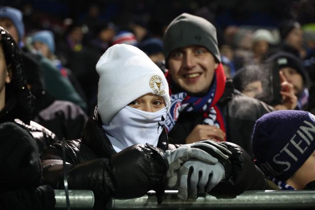 Fans of Holstein Kiel cheer for their team in a freezing cold evening prior to the start of the German Cup (DFB-Pokal) quartefinal football match between Holstein Kiel and VfB Stuttgart in Kiel, northern Germany on February 4, 2026. (Photo by Ibrahim OT / AFP) / DFB REGULATIONS PROHIBIT ANY USE OF PHOTOGRAPHS AS IMAGE SEQUENCES AND QUASI-VIDEO.