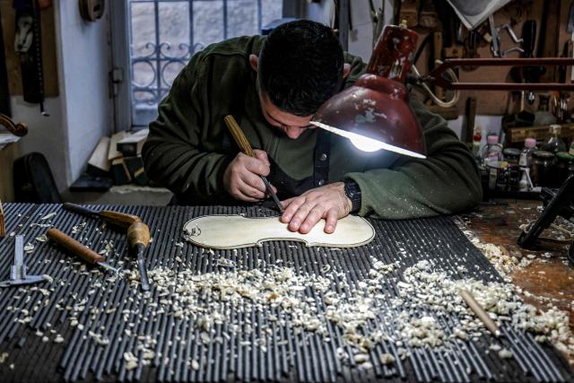 TOPSHOT - Palestinian musical instrument maker Shehada Shalalda carves the base of a violin under construction at his workshop in Ramallah in the occupied West Bank on February 4, 2026. (Photo by Zain JAAFAR / AFP)