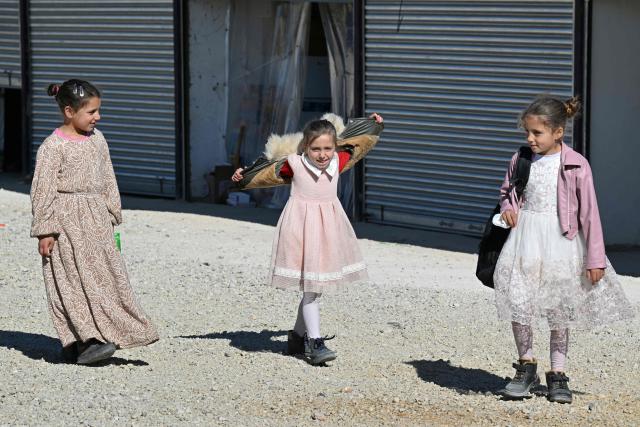 Girls stand outside shelters at the Imam Ali Housing Compound, where displaced Lebanese and Syrian refugee Shiite Muslims take refuge by the city of Hermel in Lebanon's northeastern Bekaa valley on February 4, 2026. (Photo by Joseph EID / AFP)
