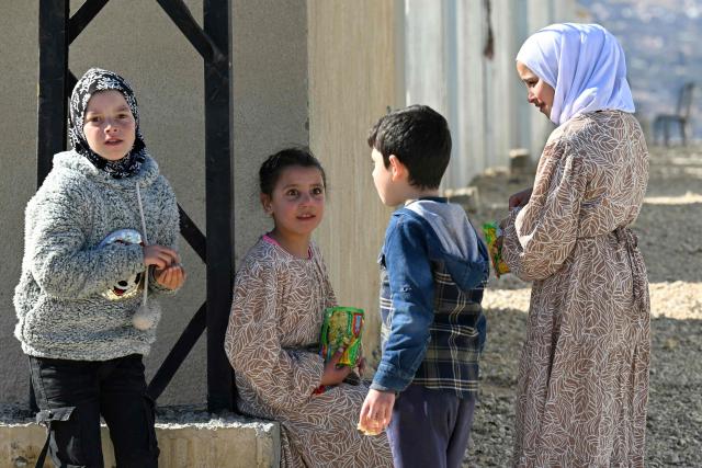 Children gather outside shelters at the Imam Ali Housing Compound, where displaced Lebanese and Syrian refugee Shiite Muslims take refuge by the city of Hermel in Lebanon's northeastern Bekaa valley on February 4, 2026. (Photo by Joseph EID / AFP)
