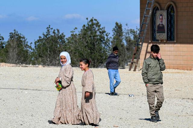 Girls and boys walk outside shelters at the Imam Ali Housing Compound, where displaced Lebanese and Syrian refugee Shiite Muslims take refuge by the city of Hermel in Lebanon's northeastern Bekaa valley on February 4, 2026. (Photo by Joseph EID / AFP)
