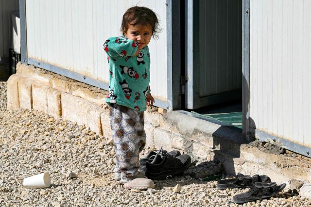 A toddler stands outside one of the shelters at the Imam Ali Housing Compound, where displaced Lebanese and Syrian refugee Shiite Muslims take refuge by the city of Hermel in Lebanon's northeastern Bekaa valley on February 4, 2026. (Photo by Joseph EID / AFP)