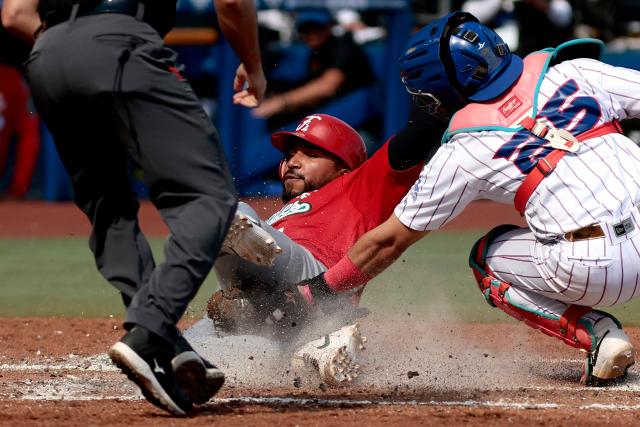 Federales de Chiriqui’s #7 Johan Camargo dives toward home plate as Leones del Escogido’s #25 Michael De La Cruz catches the ball during the third inning of the Caribbean Series baseball tournament seventh game between Panama's Federales de Chiriqui and Dominican Republic's Leones del Escogido at the Panamerican Stadium in Jalisco, Mexico, on February 4, 2026. (Photo by Ulises Ruiz / AFP)