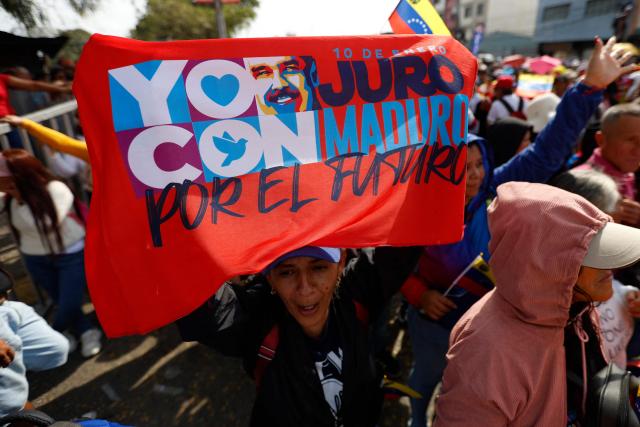 A woman shows a flag depicting ousted Venezuelan President Nicolas Maduro during a march by 'Chavismo' supporters to commemorate the 34th anniversary of a coup attempt by Hugo Chavez, in Maracay, Aragua state, Venezuela, on February 4, 2026. (Photo by Pedro MATTEY / AFP)