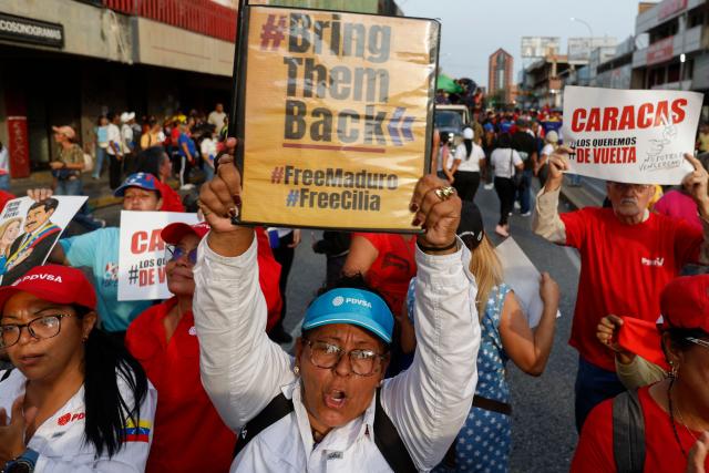 A woman shows a sign that reads "Bring them Back" during a march by 'Chavismo' supporters to commemorate the 34th anniversary of a coup attempt by Hugo Chavez, in Maracay, Aragua state, Venezuela, on February 4, 2026. (Photo by Pedro MATTEY / AFP)