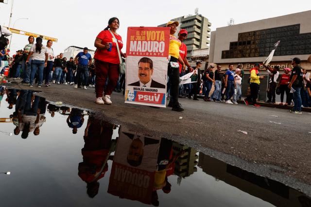Supporters show a sign depicting ousted President Nicolas Maduro during a march by 'Chavismo' supporters to commemorate the 34th anniversary of a coup attempt by Hugo Chavez, in Maracay, Aragua state, Venezuela, on February 4, 2026. (Photo by Pedro MATTEY / AFP)