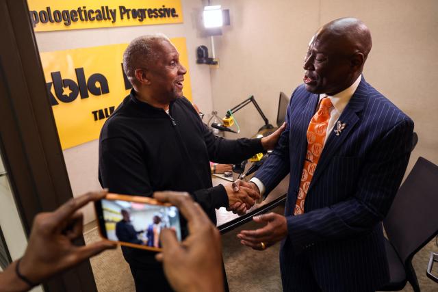 KBLA host Tavis Smiley and Attorney Ben Crump (R) greet each other after a press conference to call for accountability and stronger regulations to prevent the online video sharing platform YouTube's monetization practices, which allow the spread of false and misleading content about public figures, in Los Angeles, on February 4, 2026. (Photo by Patrick T. Fallon / AFP)