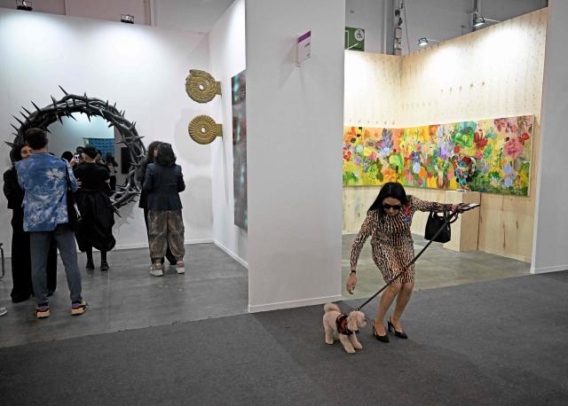 A woman with her dog on the first day of Mexico Art Week, the biggest Art fair in Latin America, drawing artists and collectors from all over the world in Mexico City on February 4, 2026. The annual fair runs from February 4 until February 8, 2026. (Photo by Carl de Souza / AFP)