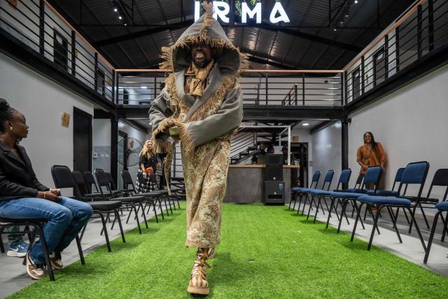 A sapeur, a member of the Société des Ambianceurs et des Personnes Élégantes (SAPE) a subculture of exceptionally stylish, elegantly dressed men and women in Brazzaville (Republic of Congo) and Kinshasa (Democratic Republic of Congo), presents a creation on the catwalk during a dress rehearsal ahead of a fashion show at the Regional Fashion Institute in Africa (IRMA) in Kinshasa, on January 31, 2026. In an old abandoned hangar, amid the dusty ballet of trucks at the port of Kinshasa, young models stride down a long strip of synthetic turf. Outside, container ships thunder. On the makeshift runway, the bass of chic electro music reverberates. For six months, nine designers from five Central African countries received free training in the basics of sewing and fashion entrepreneurship. The project, funded by the French Ministry of Foreign Affairs and carried out in partnership with the French Embassy in the DRC, aims to support more than 200 young creators by 2026. (Photo by Hardy BOPE / AFP)