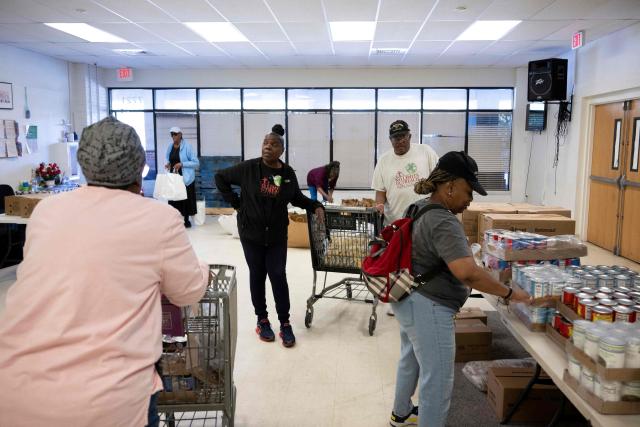 (FILES) Volunteers prepare food for distribution for furloughed federal workers at No Limits Outreach Ministries on October 21, 2025 in Hyattsville, Maryland. Although US economic growth has been solid, with US President Donald Trump's administration touting Wall Street records and tax relief, analysts warn that a "K-shaped economy" has taken hold. This is a situation where wealthier households benefit from rising asset values, but median- and lower-income families increasingly struggle. (Photo by Brendan Smialowski / AFP)