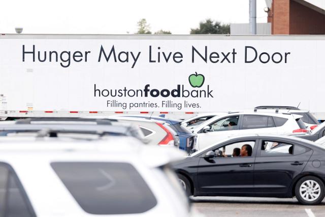 (FILES) People wait in line to receive food assistance at a turkey distribution intended for federal workers and Supplemental Nutrition Assistance Program (SNAP) recipients organized by the Houston Food Bank in Houston, Texas, on November 22, 2025. Although US economic growth has been solid, with US President Donald Trump's administration touting Wall Street records and tax relief, analysts warn that a "K-shaped economy" has taken hold. This is a situation where wealthier households benefit from rising asset values, but median- and lower-income families increasingly struggle. (Photo by Mark Felix / AFP)