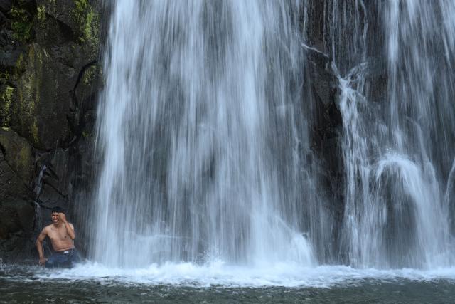A Catholic faithful bathes during the pilgrimage of the Child Jesus and the Child Zarco, in which devotees walk more than 25 km from the towns of San Ramon and Candelaria to San Pedro Nonualco, at the El Chorreron waterfall in Santa Maria Ostuma, El Salvador, on February 4, 2026. The pilgrimage, in which devotees carry two small images of Jesus, dates back more than 200 years according to historical records and represents one of the country's most important religious traditions. (Photo by Marvin RECINOS / AFP)