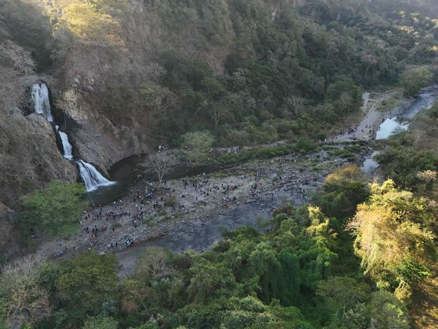 Aerial view of Catholic faithful participating in the pilgrimage of the child "Jesusito" and the child "Zarco" from the towns of San Ramon and Candelaria to San Pedro Nonualco, on the Jiboa River, in Santa Maria Ostuma, El Salvador, on February 4, 2026. The pilgrimage, in which devotees carry two small images of Jesus, dates back more than 200 years according to historical records and represents one of the country's most important religious traditions. (Photo by Marvin RECINOS / AFP)