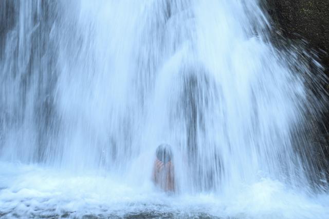 TOPSHOT - A Catholic faithful bathes during the pilgrimage of the Child Jesus and the Child Zarco, in which devotees walk more than 25 km from the towns of San Ramon and Candelaria to San Pedro Nonualco, at the El Chorreron waterfall in Santa Maria Ostuma, El Salvador, on February 4, 2026. The pilgrimage, in which devotees carry two small images of Jesus, dates back more than 200 years according to historical records and represents one of the country's most important religious traditions. (Photo by Marvin RECINOS / AFP)