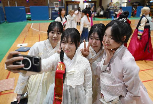 South Korean students wearing traditional hanbok dresses pose for a selfie after a graduation and coming-of-age ceremony at a girls' high school in Seoul on February 5, 2026. Around 300 students attended the event, which symbolises the transition of children into adulthood and aims to teach participants manners and responsibility. (Photo by Jung Yeon-je / AFP)