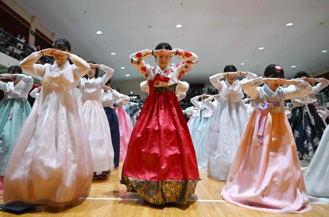 South Korean students wearing traditional hanbok dresses bow as they attend a graduation and coming-of-age ceremony at a girls' high school in Seoul on February 5, 2026. Around 300 students attended the event, which symbolises the transition of children into adulthood and aims to teach participants manners and responsibility. (Photo by Jung Yeon-je / AFP)