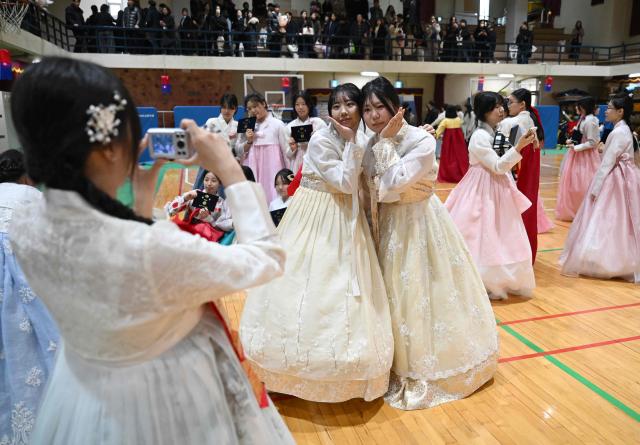 South Korean students wearing traditional hanbok dresses pose for a selfie after a graduation and coming-of-age ceremony at a girls' high school in Seoul on February 5, 2026. Around 300 students attended the event, which symbolises the transition of children into adulthood and aims to teach participants manners and responsibility. (Photo by Jung Yeon-je / AFP)
