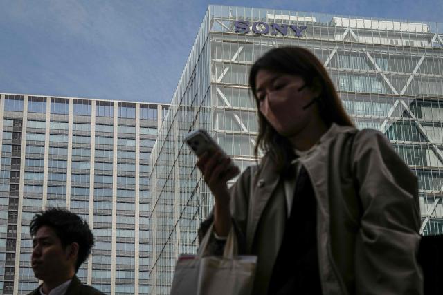 People walk past the Sony headquarters in Tokyo on February 5, 2025. Japanese giant Sony on February 5, 2026 hiked its full-year net profit forecast thanks to strong performances in its video games and music divisions. (Photo by Yuichi YAMAZAKI / AFP)