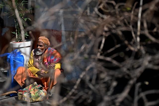 A man sits under the sun, along a road in New Delhi on February 5, 2026. (Photo by Sajjad HUSSAIN / AFP)