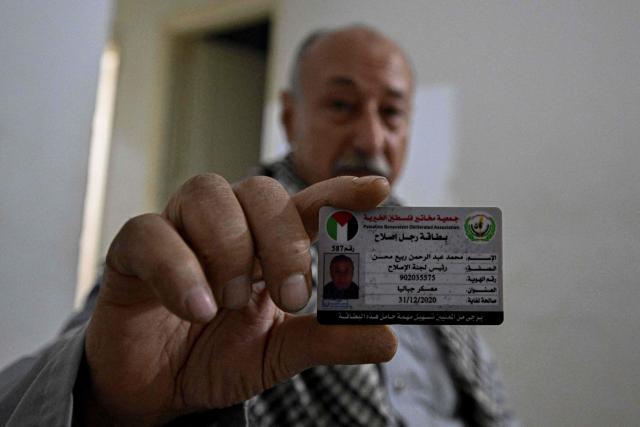 Palestinian Mahmoud Abdelrahman Rabie, who has been stranded in Egypt, shows his membership card of the Palestinian charitable organization he worked for, during an interview with AFP at his rental apartment on the eastern outskirts of Cairo on February 2, 2026. As Israel begins to allow a trickle of Palestinians through the Rafah border crossing, Gazans stranded in Egypt are torn between staying in exile without formal status or returning to a land in ruins. (Photo by Khaled DESOUKI / AFP)