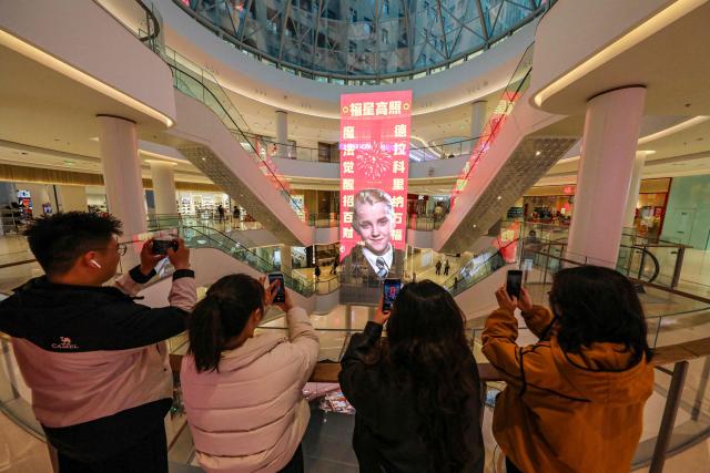 People take photos of a giant Lunar New Year poster featuring English actor Tom Felton posing as Draco Malfoy, a character from the Harry Potter movies series, at a shopping mall in Shangqiu, in China’s central Henan province on February 5, 2026. The character has become popular in China in the buildup to the Year of the Horse because the transliteration of his surname contains the Chinese characters for "horse" and "good fortune", making him an auspicious omen for the year ahead. (Photo by AFP) / China OUT