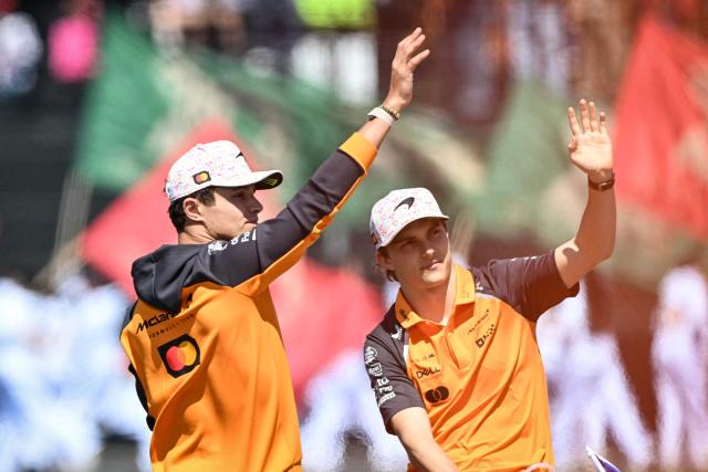(FILES) McLaren's British driver Lando Norris (L) and Australian driver Oscar Piastri (R) wave to fans during the drivers' parade ahead of the Mexico City Formula One Grand Prix at the Hermanos Rodriguez racetrack in Mexico City on October 26, 2025. Before facing off again on the Formula 1 circuits, the McLaren duo are putting their rivalry, which began in 2025, behind them, with Oscar Piastri assuring that he will be treated “fairly” and world champion Lando Norris displaying his serenity. (Photo by Yuri CORTEZ / AFP)