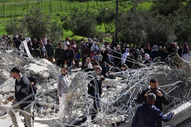 Palestinians gather to look at the concrete and steel debris from homes and shops after bulldozers protected by Israeli security forces demolished residential buildings belonging to Palestinian families in Beit Aawa, west the Israeli-occupied West Bank city of Hebron on February 5, 2026. Israel, whose army has occupied the West Bank since 1967, regularly demolishes the homes of Palestinians accused of carrying out deadly attacks against Israelis and of not having construction permits issued by Israel. The government defends the deterrent effect of these demolitions, but critics denounce the practice as a form of collective punishment that leaves families homeless. (Photo by HAZEM BADER / AFP)