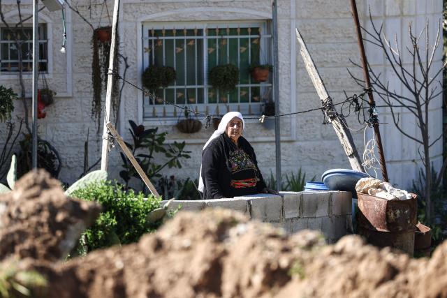 A Palestinian woman stands in the yard of her home as shops and homes belonging to Palestinian families are destroyed by bulldozers protected by Israeli security forces in Beit Aawa, west the Israeli-occupied West Bank city of Hebron on February 5, 2026. Israel, whose army has occupied the West Bank since 1967, regularly demolishes the homes of Palestinians accused of carrying out deadly attacks against Israelis and of not having construction permits issued by Israel. The government defends the deterrent effect of these demolitions, but critics denounce the practice as a form of collective punishment that leaves families homeless. (Photo by HAZEM BADER / AFP)