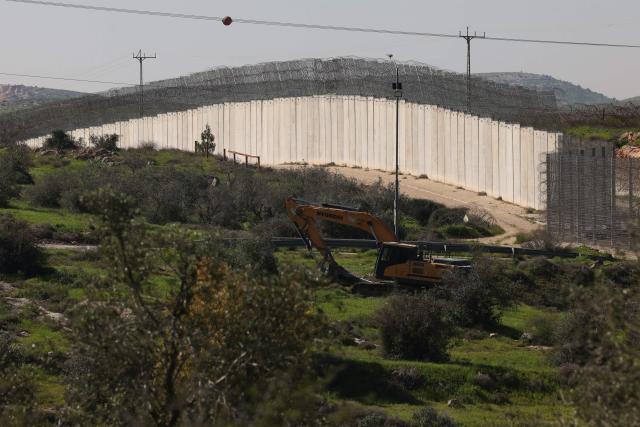The Israeli built controversial separation barrier is seen passing through fields near the Palestinian village of Beit Aawa, west the Israeli-occupied West Bank city of Hebron on February 5, 2026. The barrier is a combination of concrete walls and wire fences running north to south that Israel says is necessary to protect it self from Palestinian militants. However, large sections of it encroach on the West Bank, and the Palestinians call it a land grab. The International Court of Justice issued a non-binding ruling in 2004 that parts of the barrier in the West Bank are illegal and should be removed. The barrier is supposed to follow the Green Line that marks Israel's borders before the 1967 Six Day War, when the Jewish state captured the Golan Heights, east Jerusalem, the Gaza Strip and the West Bank. (Photo by HAZEM BADER / AFP)