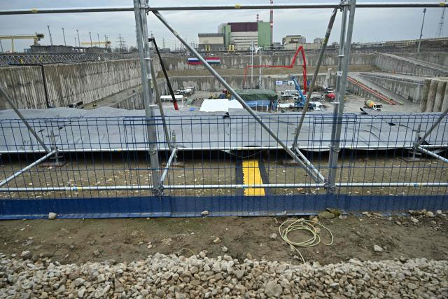 An overview shows Hungarian (R) and Russian (L) national flags on a wall, workers and vehicles at the Paks II site near the city of Paks, southern Hungary, on February 5, 2026, as concreting begins on the foundation plate of the first technological building on the nuclear island of Unit 5, officially marking the start of the physical construction of Paks II. Workers poured concrete for a new reactor near Hungary's sole nuclear plant beginning a contentious expansion project led by Russia's Rosatom following a decade of delays.
Hungary struck an agreement with Russia in 2014 involving a 10 billion euro ($11 billion) loan deal to build two reactors at the Paks plant south of Budapest. (Photo by Attila KISBENEDEK / AFP)
