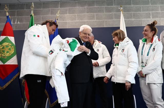 Italian President Sergio Mattarella (2nd L) puts on an Italian delegation Olympic jacket as he visits the Olympic Village ahead of the Milano Cortina 2026 Winter Olympic Games in Milan, on February 5, 2026. (Photo by Yara Nardi / POOL / AFP)