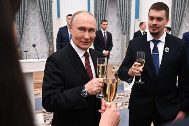 In this pool photograph distributed by the Russian state agency Sputnik, Russia's President Vladimir Putin toasts with honourees after a ceremony presenting awards to young scientists at the Kremlin in Moscow on February 5, 2026. (Photo by Kristina Solovyova / POOL / AFP)