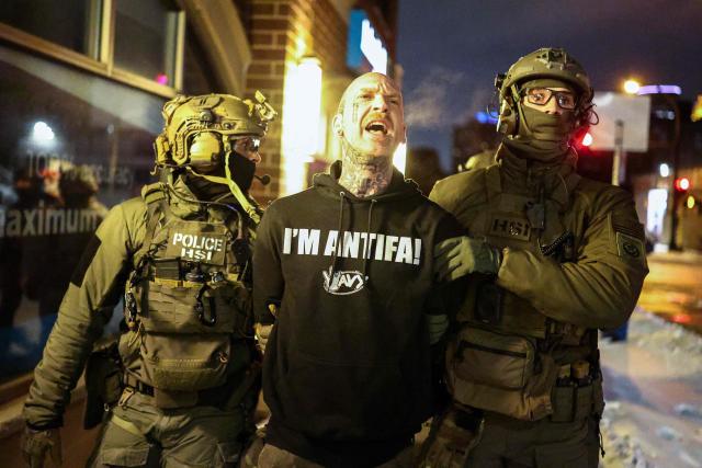 Federal agents with Homeland Security Investigations (HSI) detain a protestor wearing an "Antifa" shirt outside a residential building in Minneapolis, Minnesota, on February 5, 2026. US President Donald Trump suggested on February 4 that a "softer touch" may be needed on immigration, as his administration said 700 federal officers would be pulled from Minnesota but that mass deportations would not stop. The fatal shootings of two protesters by federal officers in Minneapolis last month sparked widespread outrage in the United States and calls for an end to immigration raids in the Midwestern city, but Trump's administration has been reluctant to shift course. (Photo by Charly TRIBALLEAU / AFP)