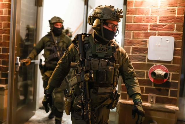 Federal agents with Homeland Security Investigations (HSI) exit a residential building as they seek to detain a protestor in Minneapolis, Minnesota, on February 5, 2026. US President Donald Trump suggested on February 4 that a "softer touch" may be needed on immigration, as his administration said 700 federal officers would be pulled from Minnesota but that mass deportations would not stop. The fatal shootings of two protesters by federal officers in Minneapolis last month sparked widespread outrage in the United States and calls for an end to immigration raids in the Midwestern city, but Trump's administration has been reluctant to shift course. (Photo by CHARLY TRIBALLEAU / AFP)