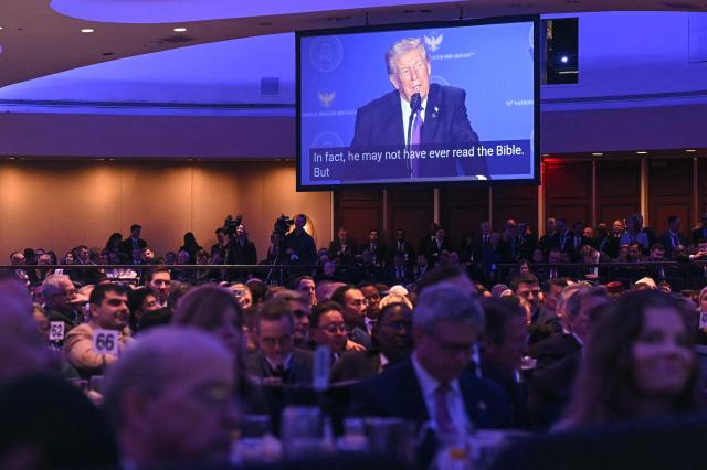 Attendees listen as US President Trump, displayed on a screen, speaks during the National Prayer Breakfast at the Washington Hilton in Washington, DC on February 5, 2026. (Photo by SAUL LOEB / AFP)