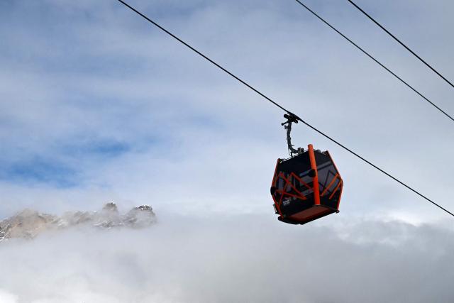 A cable car passes with the peaks of the Dolomites in the distance during the Milano Cortina 2026 Winter Olympic Games in Cortina d'Ampezzo on February 5, 2026. (Photo by Stefano RELLANDINI / AFP)