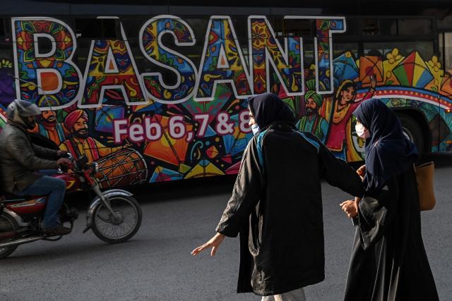 Women walk past a bus decorated with the theme of the Basant Festival in Lahore on February 5, 2026. (Photo by Arif ALI / AFP)