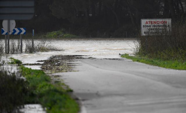 A sign reads "Caution - Flood-Prone Area - Guadalete River Floods" as floodwaters cover a road at Las Pachecas settlement in Jerez, southern Spain, on February 5, 2026, amid Storm Leonardo. Spain today lifted its highest weather alert for torrential rain in the southern region of Andalusia, where a woman went missing, a day after the storm killed one in Portugal. Storm Leonardo dumped more than 40 centimetres (15 inches) of rain in some Andalusian districts yesterday, forcing the evacuation of thousands, paralysing rail and road transport and shutting schools. The downpours, which came after a storm killed five people and left hundreds injured in neighbouring Portugal last week, are examples of extreme weather that scientists say climate change is worsening. (Photo by CRISTINA QUICLER / AFP)